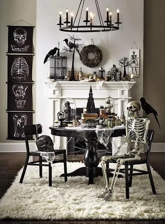 a vintage Halloween space with black posters, skeletons and skulls, blackbirds and wreaths, black furniture and a candle chandelier is wow