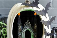 a Halloween diorama pumpkin with a castel, skeletons, lights and bats on one side is a hot idea that can be easily crafted