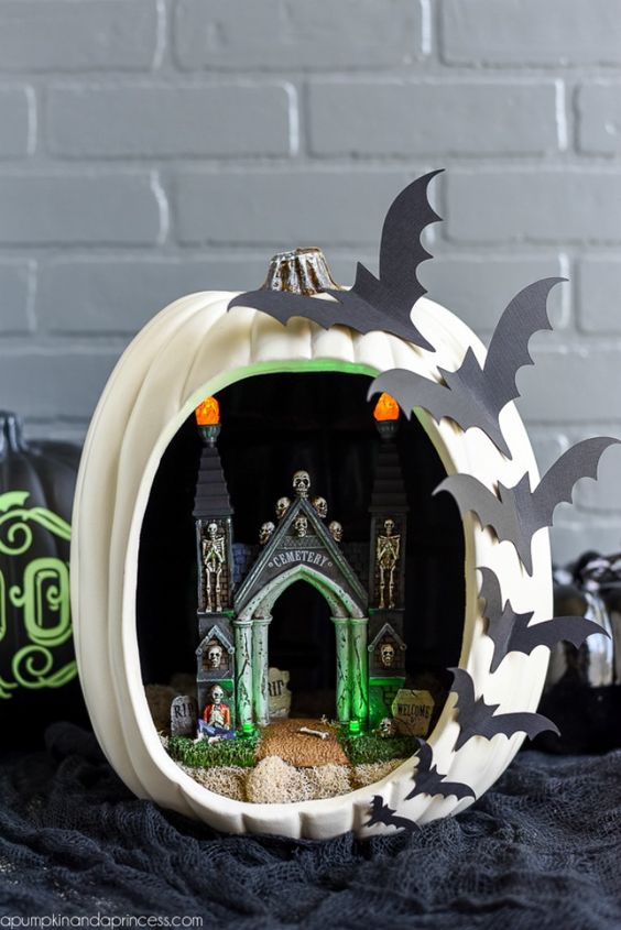 a Halloween diorama pumpkin with a castel, skeletons, lights and bats on one side is a hot idea that can be easily crafted
