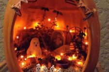 a Halloween diorama with a banner, lights, ghosts, a fence, bats, hay and planters is a gorgeous solution for this holiday