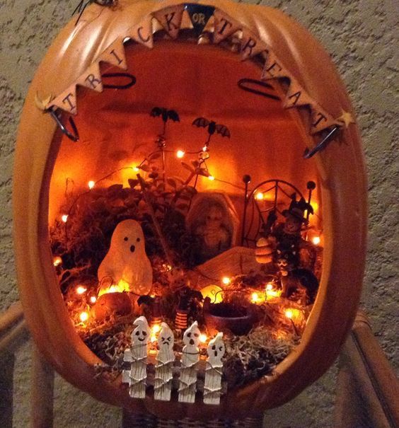 a Halloween diorama with a banner, lights, ghosts, a fence, bats, hay and planters is a gorgeous solution for this holiday