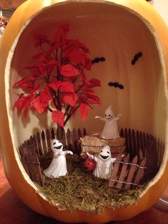 a Halloween diorama with a red leaf tree, ghosts and hay plus a fence and bats on the wall is a creative and bright solution