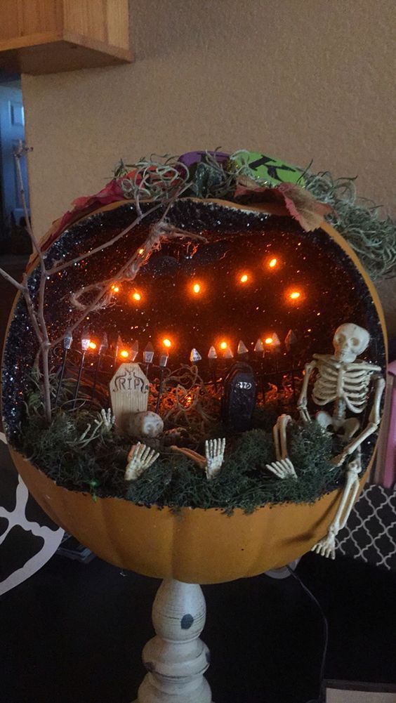 a Halloween pumpkin diorama with lights, skeletons, graveyards and branches and moss on the floor is a lovely idea