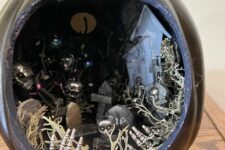 a black Halloween diorama with skeleton hands and skulls, trees, a house and a moon is a lovely and catchy idea to go for