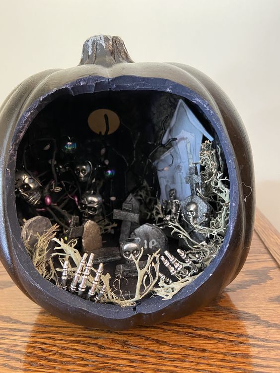 a black Halloween diorama with skeleton hands and skulls, trees, a house and a moon is a lovely and catchy idea to go for