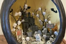 a black pumpkin with a castle, hay, skull lights and a graveyard is a lovely diorama idea for Halloween