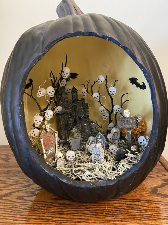 a black pumpkin with a castle, hay, skull lights and a graveyard is a lovely diorama idea for Halloween