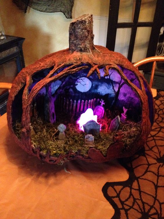 a moody and scary Halloween pumpkin with a purple sky, a fence, some scary trees, a ghost and some tombstones is wow