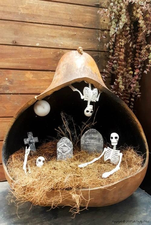 a pumpkin diorama with hay, a graveyard, skeletons and skulls and a moon is a unique solution that will catch an eye