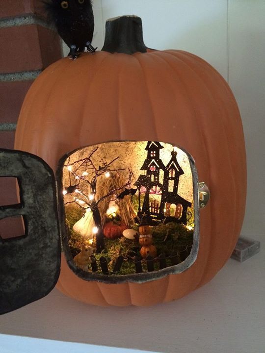 a small Halloween pumpkin diorama with a black painted house, a black tree with lights, moss, pumpkins and bats