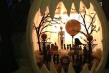 a white Halloween pumpkin diorama with a skeleton, pumpkins, trees, hat and tombstones plus lights is amazing