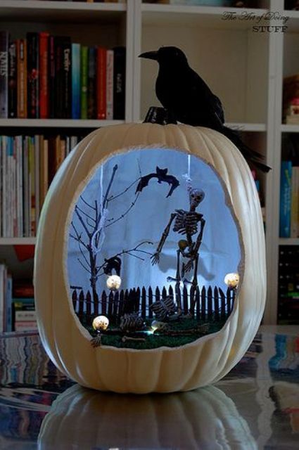 a white Halloween pumpkin with a black skeleton, a tree, a fence, bats and a black cat, skulls and lights is amazing