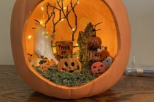 an orange Halloween pumpkin diorama with hat, mini pumpkins, ghosts, lights and branches is a lovely decoration for a kids’ party