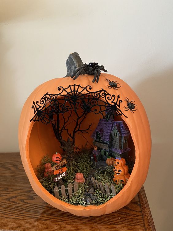 an orange pumpkin with a haunted house, hay and a scary tree plus a number of jack-o-lanterns is a great idea for Halloween