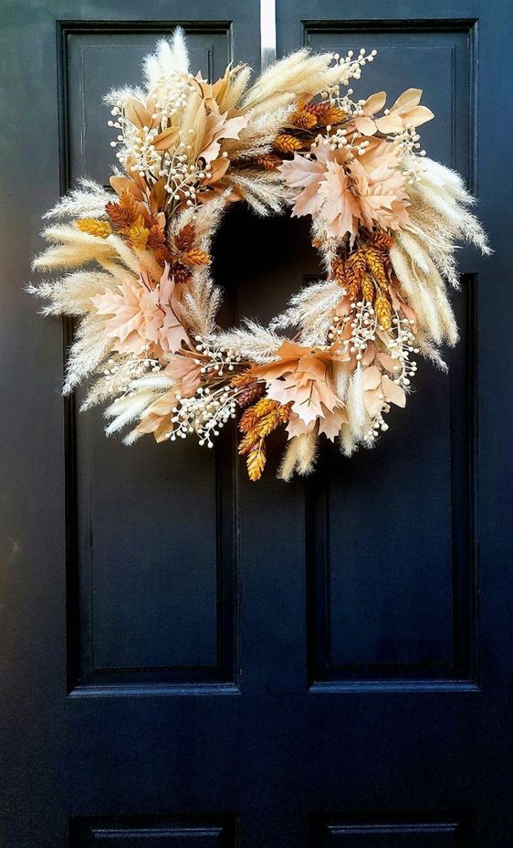 a beautiful Thanksgiving wreath of grasses, berries, dried blooms and leaves looks very chic, cozy and lovely