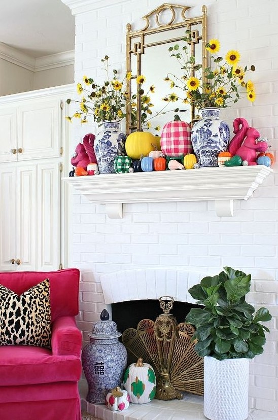 a bold and bright fall mantel with colorful pumpkins, plaid and color block ones plus yellow blooms in vases is amazing