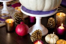 03 a bold Thanksgiving tablescape with gilded pinecones, a white pumpkin on a purple stand, fuchsia napkins and pomegranats, purple candleholders