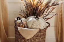 04 a boho Thanksgiving decoration of a basket with faux pumpkins, some grasses and wheat is a cool and cozy solution