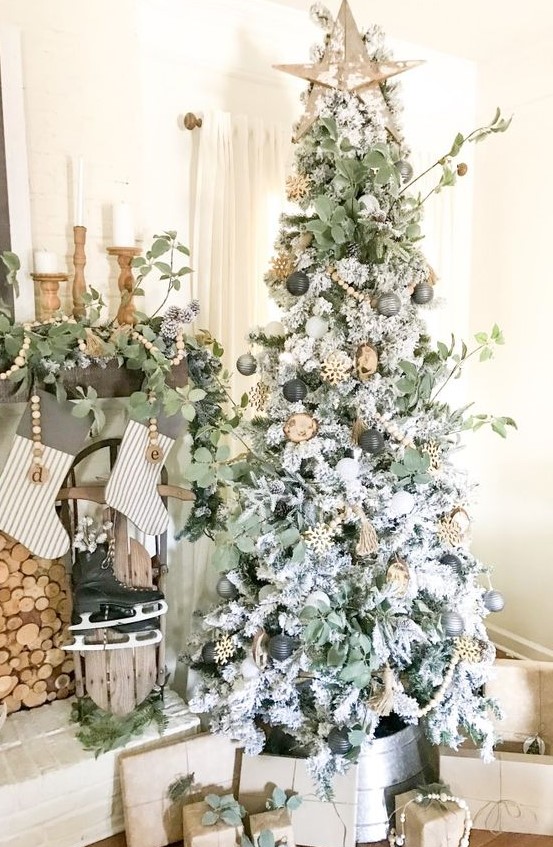 a boho Christmas tree with gold, grey and black ornaments, greenery, a wooden star on top and wooden beads and snowflakes