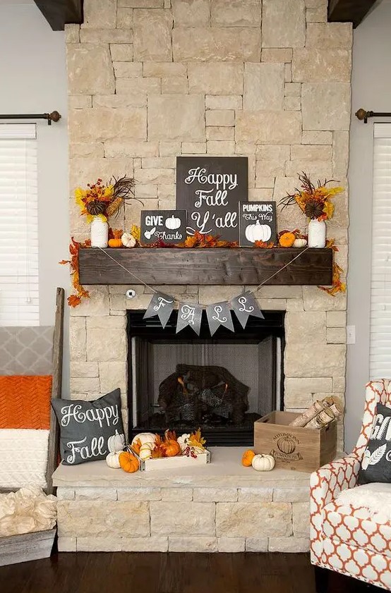 a bold Thanksgiving mantel with lots of dried leaves, wheat, pumpkins of various materials, garlands and several signs