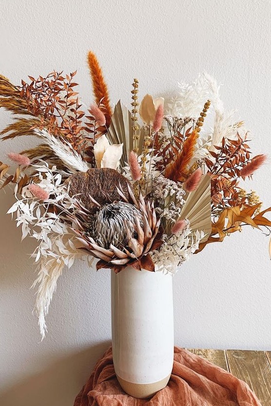 a bright boho Thanksgiving centerpiece with dried leaves, bunny tails and various blooms and fronds