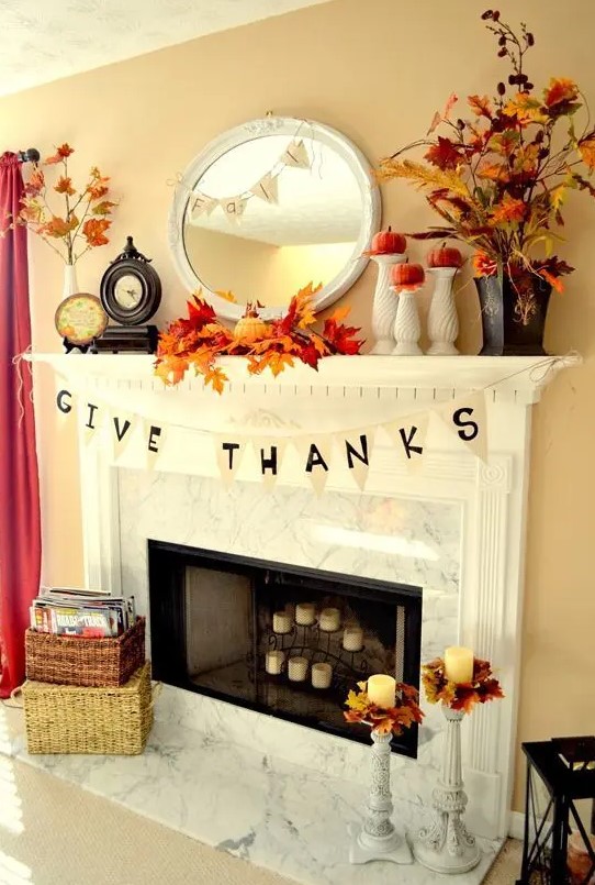 a bright rustic Thanksgiving mantel with bold leaf arrangements, pumpkins on stands, some banners and candles in candleholders