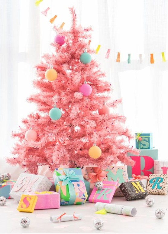 a cool candy pink Christmas tree decorated with a bit of pastel-colored ornaments looks gorgeous, modern, fresh and very pretty