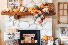 09 a cozy and chic Thanksgiving mantel with lots of pumpkins, a basket, a plaid blanket, a sign and some pumpkins in a crate