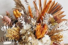 a fantastic Thanksgiving centerpiece of king proteas, berries, dried blooms, grasses and leaves spray painted