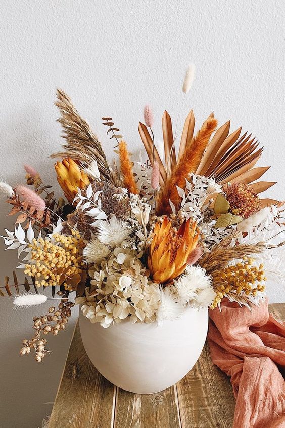 a fantastic Thanksgiving centerpiece of king proteas, berries, dried blooms, grasses and leaves spray painted
