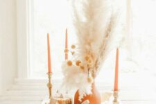10 a neutral boho Thanksgiving centerpiece of wooden pumpkins, a terracotta vase and candles, dried grasses, lights and leaves