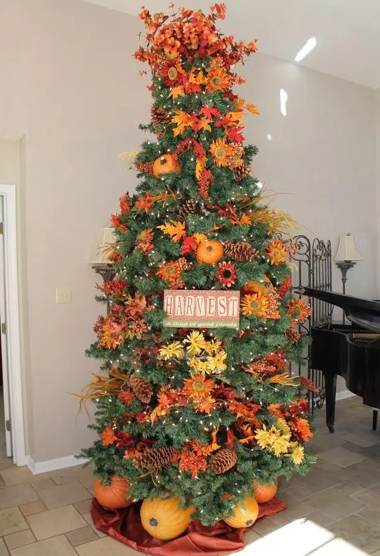 a gorgeous and bright Thanksgiving tree with lights, pinecones, bright faux blooms and leaves, branches, a sign and pumpkins