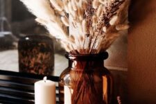 12 boho meets rustic Thanksgiving decor with woven pumpkins, a large brown vase with pampas grass and various candles