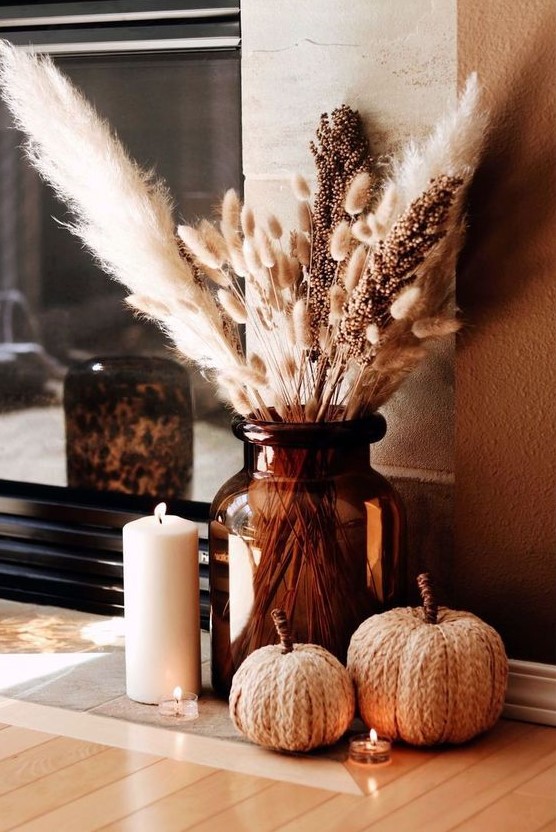 boho meets rustic Thanksgiving decor with woven pumpkins, a large brown vase with pampas grass and various candles