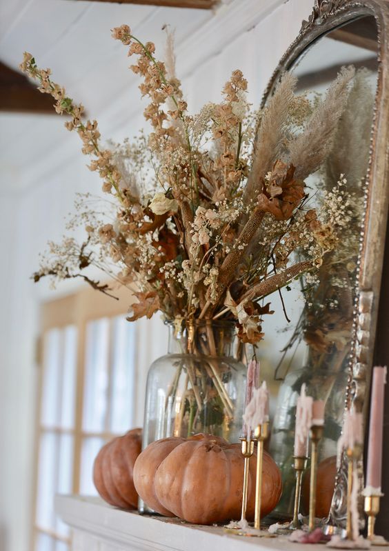 boho Thanksgiving decor with dried blooms, leaves and grasses, some natural pumpkins and pink candles