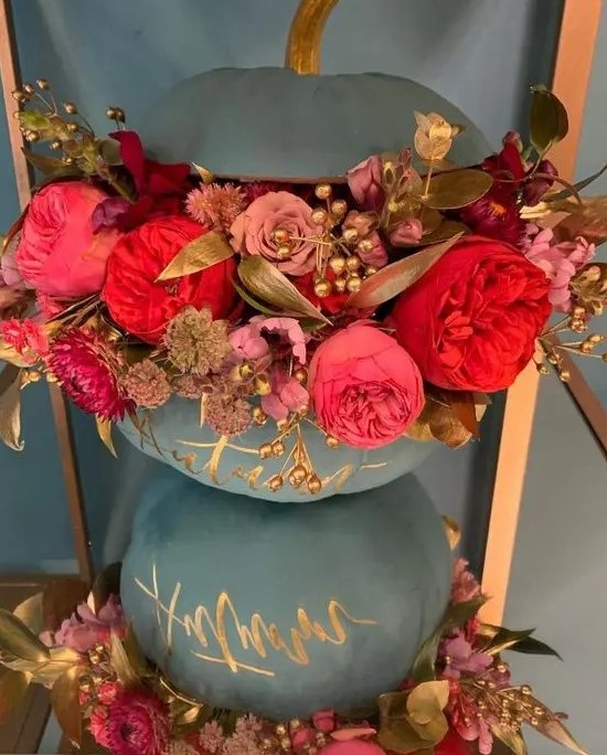 a matte grey pumpkin decorated with gold calligraphy, pink, mauve and deep red blooms, gilded leaves and berries