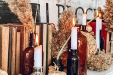 14 boho Thanksgiving decor with neutral pumpkins and dried blooms, white candles in dark apothecary bottles and vintage books