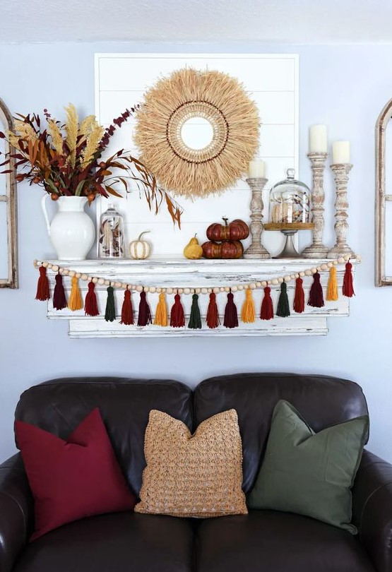 bright boho Thanksgiving decor with a bright tassel and wooden bead garland, wooden candleholders, a wheat wreath and some bold branches