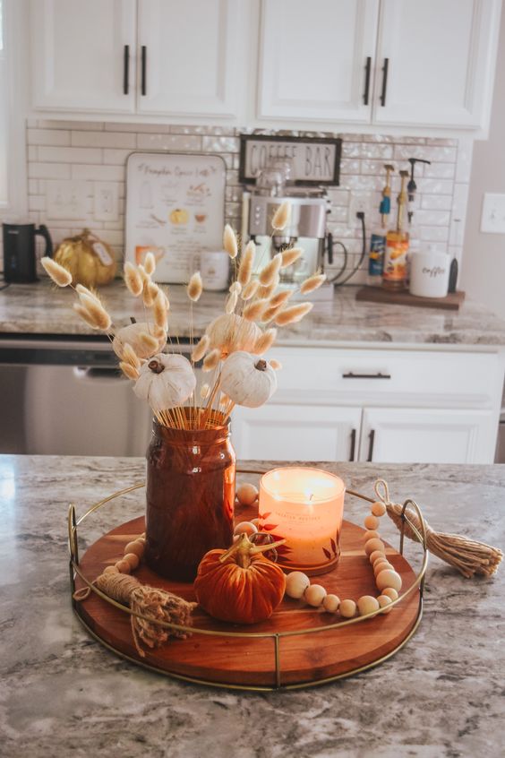 pretty boho Thanksgiving decor on a tray, with an apothecary jar with bunny tails, fabric pumpkins and a candle