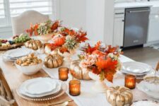 19 a bold Thanksgiving table setting with bright fall leaves and gilded pumpkins, amber candleholders and white porcelain