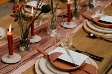 20 a beautiful Thanksgiving table setting with a rust-colored runner and napkins, wood slice placemats, rust candles and dried blooms