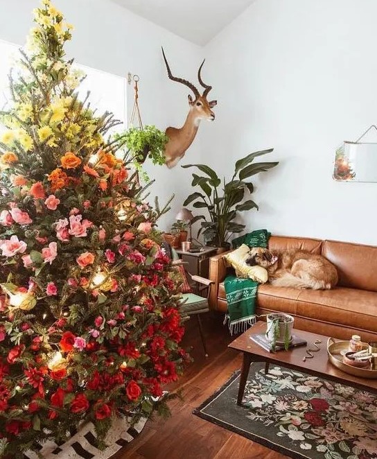 a fantastic gradient Christmas tree decorated with yellow, pink and red blooms and leaves plus lights is lovely