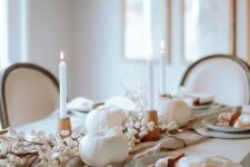 21 a beautiful Thanksgiving tablescape with white candles and pumpkins, grey plates and neutral linens, wooden candleholders and berries