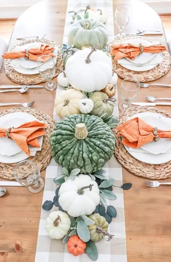 a bright and fun Thanksgiving table with leaves, pastel and white pumpkins, woven chargers and orange napkins