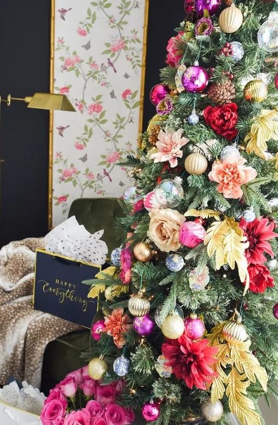a glam Christmas tree decorated with pink, red, peachy and yellow blooms, leaves, shiny metallic and bold ornament and pinecones