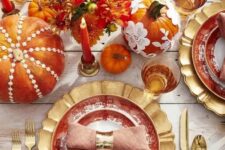22 a bright and whimsy Thanksgiving tablescape with gold chargers, cutlery, colorful pumpkins and floral arrangements, bold candles