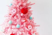 22 a pink Christmas tree with mini blue and green ornaments, with red paper balls and pink donut ornaments is a fun candy-inspired decor idea