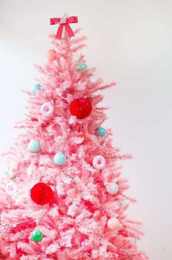 a pink Christmas tree with mini blue and green ornaments, with red paper balls and pink donut ornaments is a fun candy-inspired decor idea