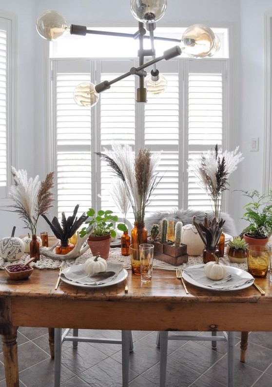 a boho Thanksgiving tablescape with large plates and white pumpkins, folk sharpie pumpkins, pampas grass and potted cacti
