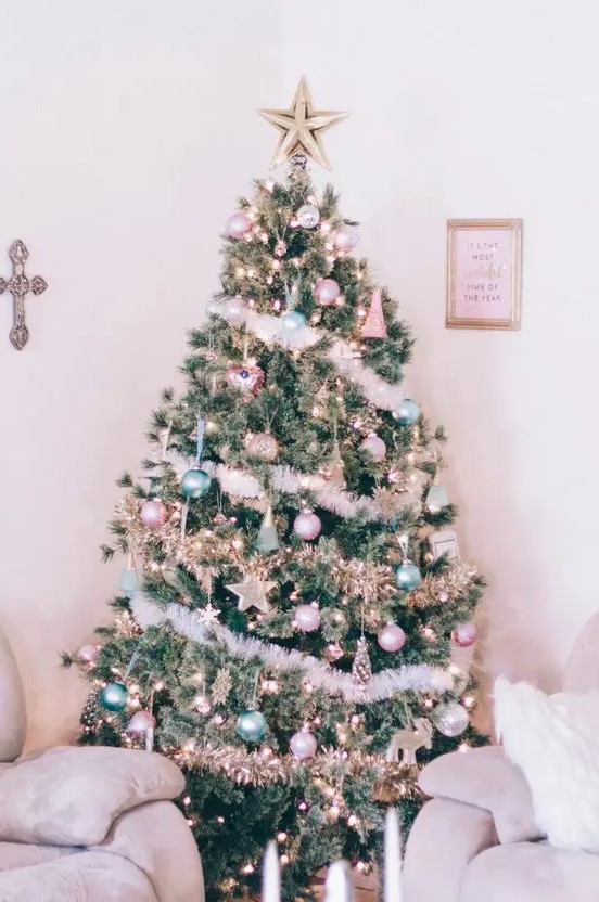 a Christmas tree decorated with pastel green and pink ornaments, stars, lights and fluffy garlands plus a star topper